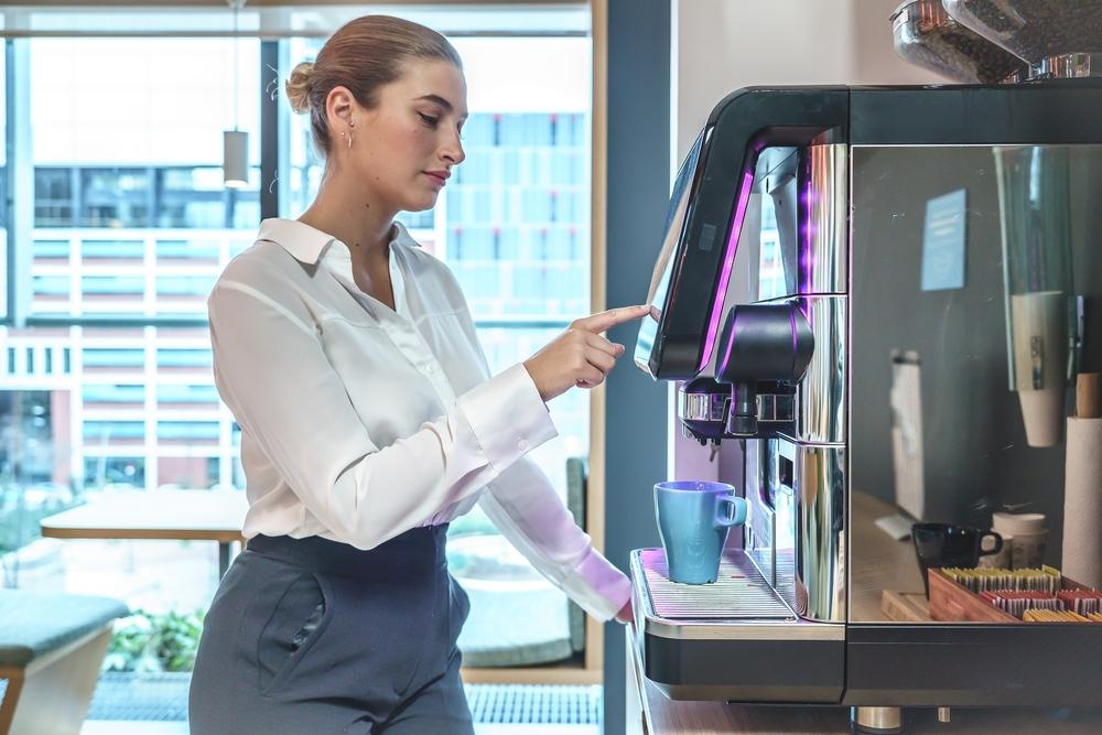 Työntekijä ottaa kahvia kahviautomaatista